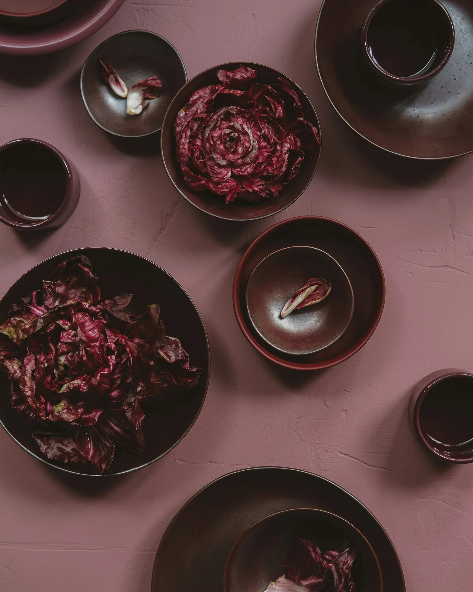 Radicchio in dark stoneware bowls on a rose plaster table